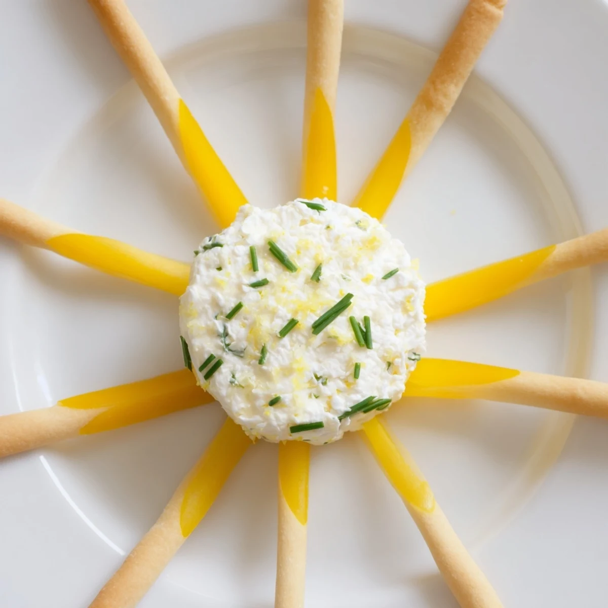 A bright Tuscan Sunburst appetizer: Yellow bell peppers arranged with creamy lemon goat cheese and breadsticks.