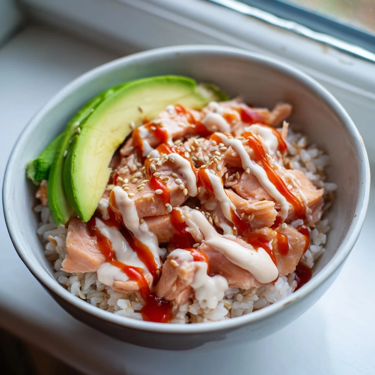 Steaming Emily Mariko salmon rice bowl topped with green onions and sesame seeds beside nori strips for wrapping.