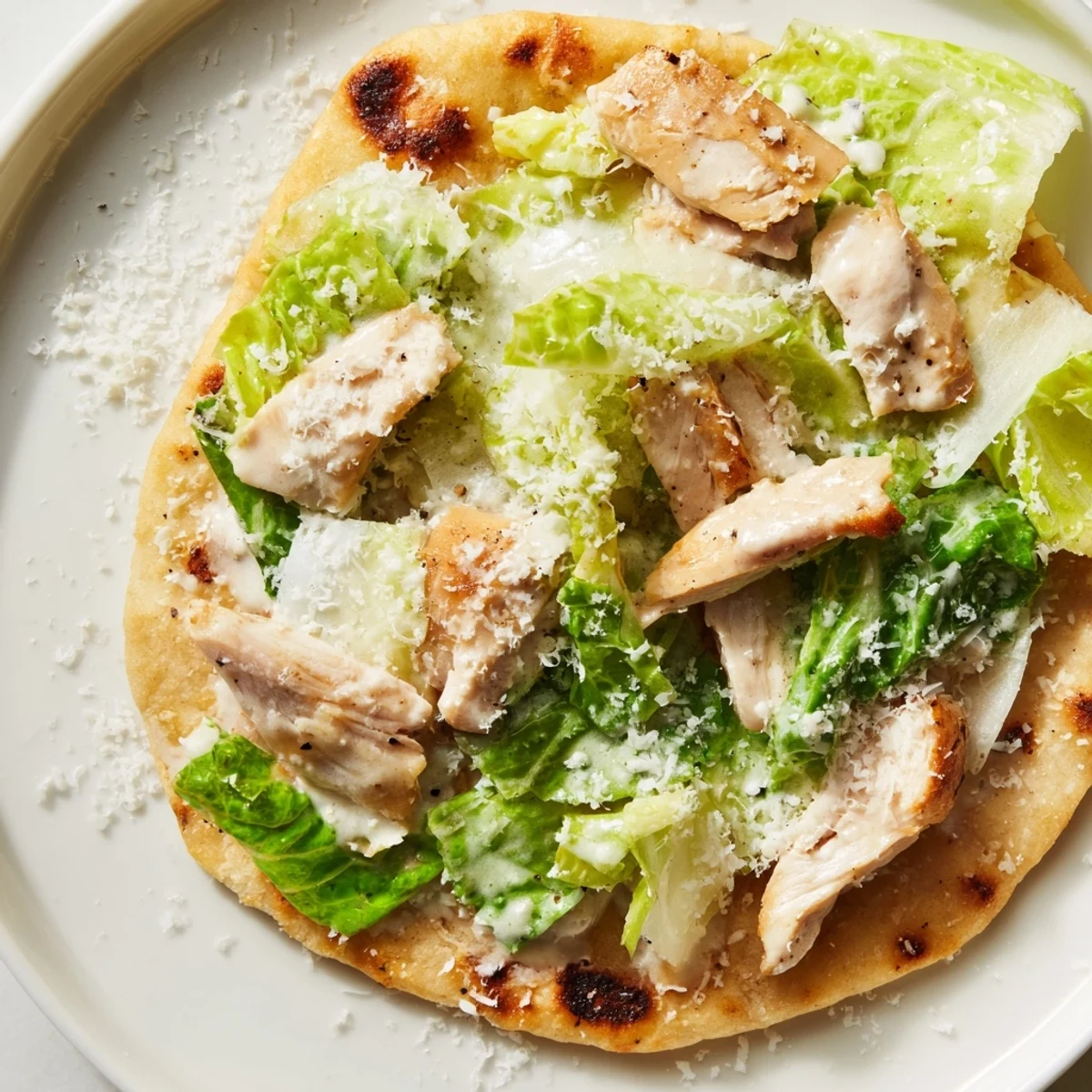 Golden-brown Chicken Caesar Flatbread topped with grilled chicken, crisp romaine, and creamy Caesar dressing, served warm on a rustic wooden board.