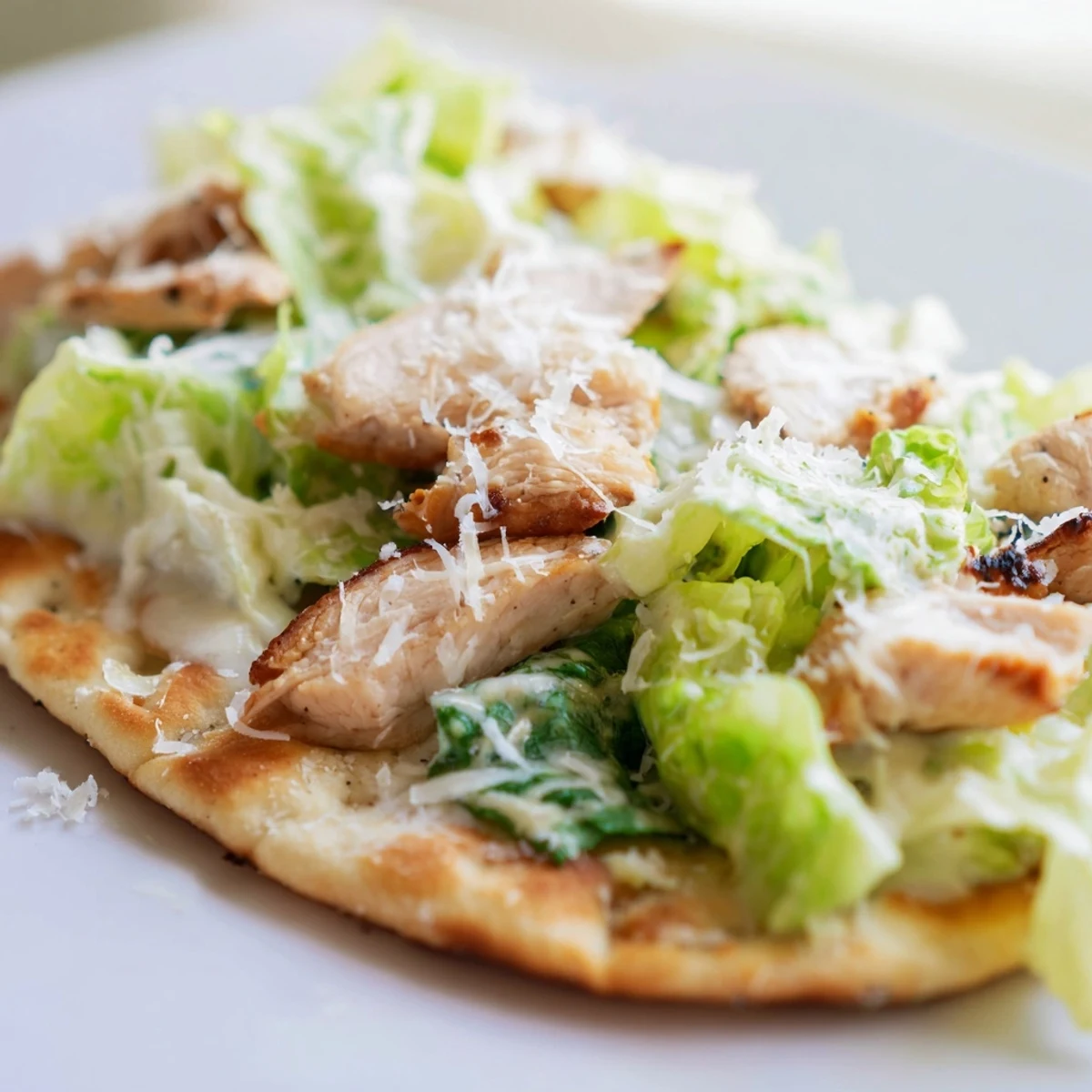 Freshly baked Chicken Caesar Flatbread featuring tender sliced chicken, shaved parmesan, and bright cherry tomatoes for a colorful, appetizing meal.