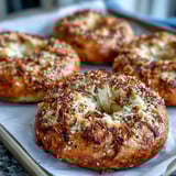 Four warm Greek Yogurt Bagels topped with sesame seeds and shredded cheese, ready to serve for a healthy breakfast.