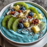 Creamy blue spirulina smoothie bowl, beautifully adorned with fresh pineapple and kiwi slices.