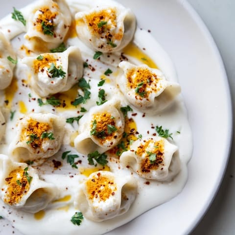 Close-up of golden brown Turkish cheesy manti ready to eat, served with vibrant red spiced butter.
