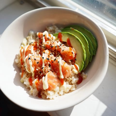 Freshly assembled Emily Mariko salmon rice bowl featuring seasoned rice, crispy seaweed sheets, and sliced avocado.