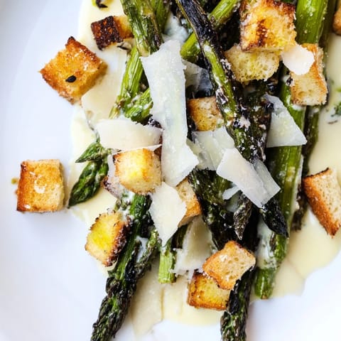 Fresh roasted asparagus Caesar salad featuring tangy yogurt dressing, homemade croutons, and shaved Parmesan garnish.