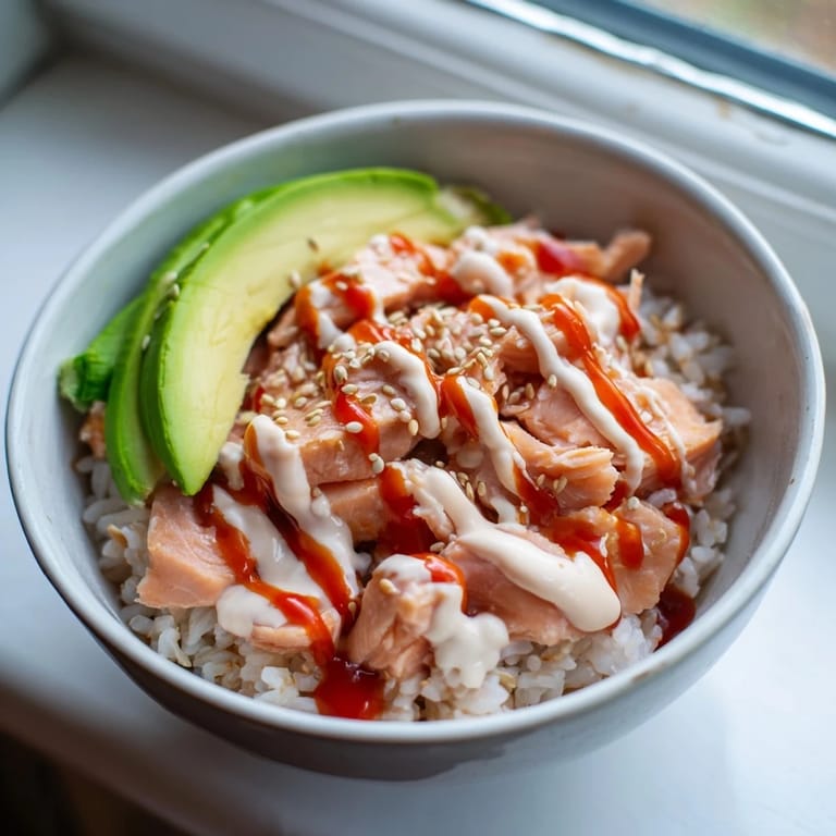 Steaming Emily Mariko salmon rice bowl topped with green onions and sesame seeds beside nori strips for wrapping.