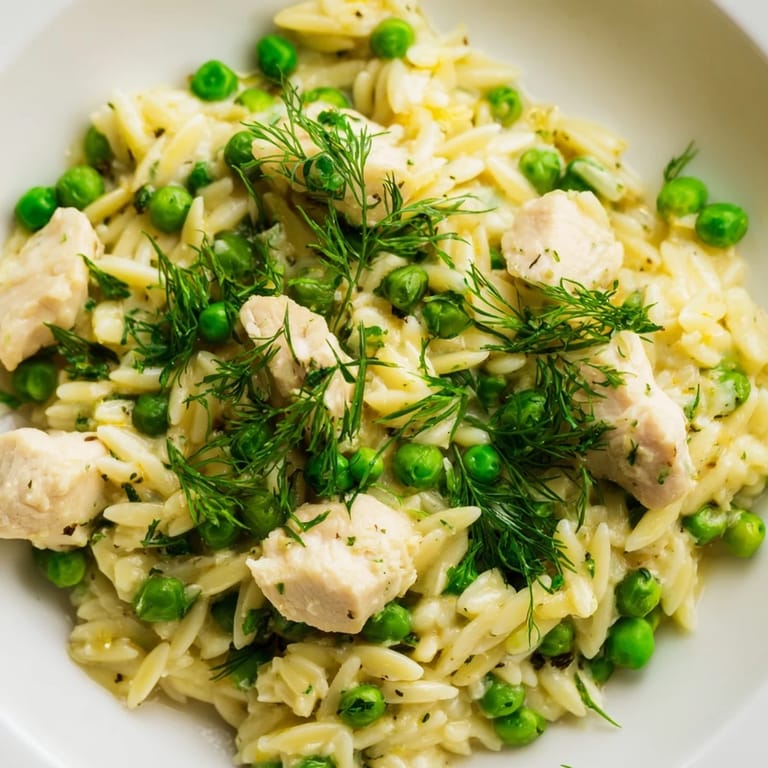 A serving of Lemon Herb Chicken Orzo Skillet garnished with fresh dill and parsley, ready to enjoy on a spring dinner table.