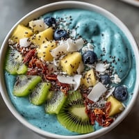 Vibrant blue spirulina smoothie bowl bursting with fresh, colorful tropical fruit toppings.
